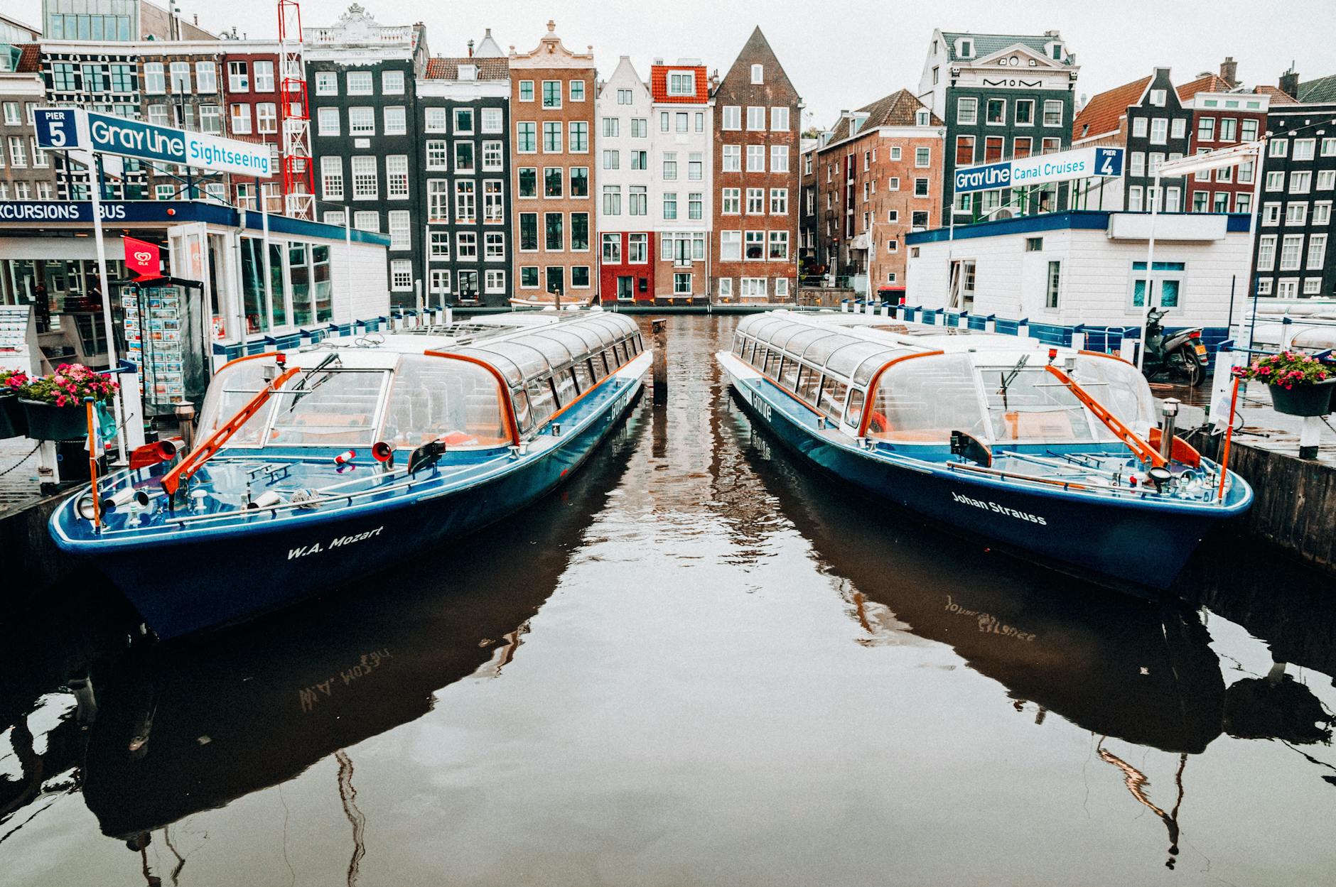 A canal cruise boat passing under a bridge in Amsterdam