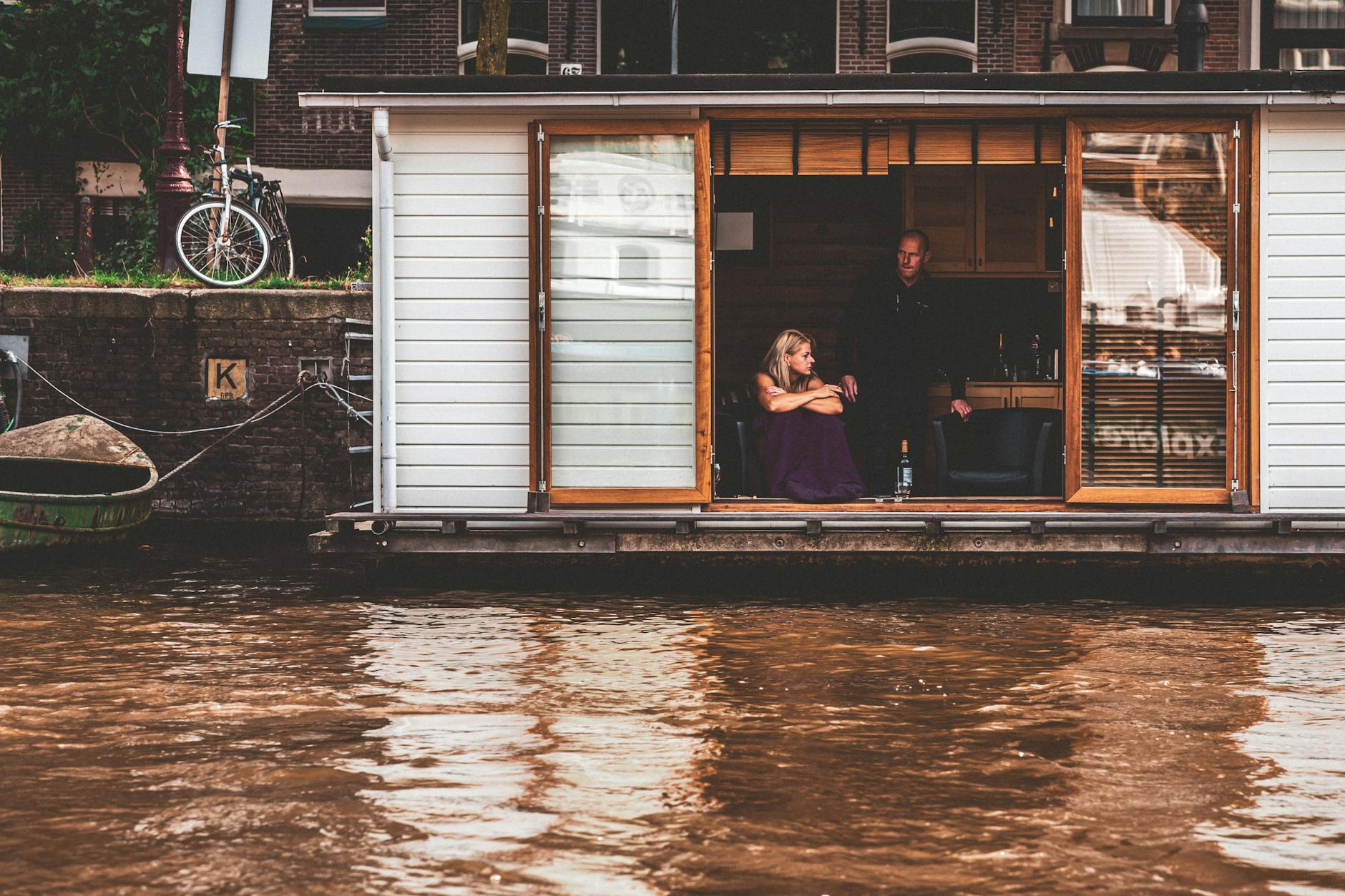 A traditional Amsterdam houseboat moored along one of the city's famous canals, offering a unique accommodation experience for tourists looking for where to stay in Amsterdam