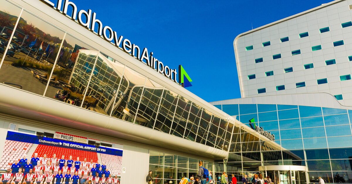 The glass terminal building at Eindhoven Airport with passengers outside the entrance