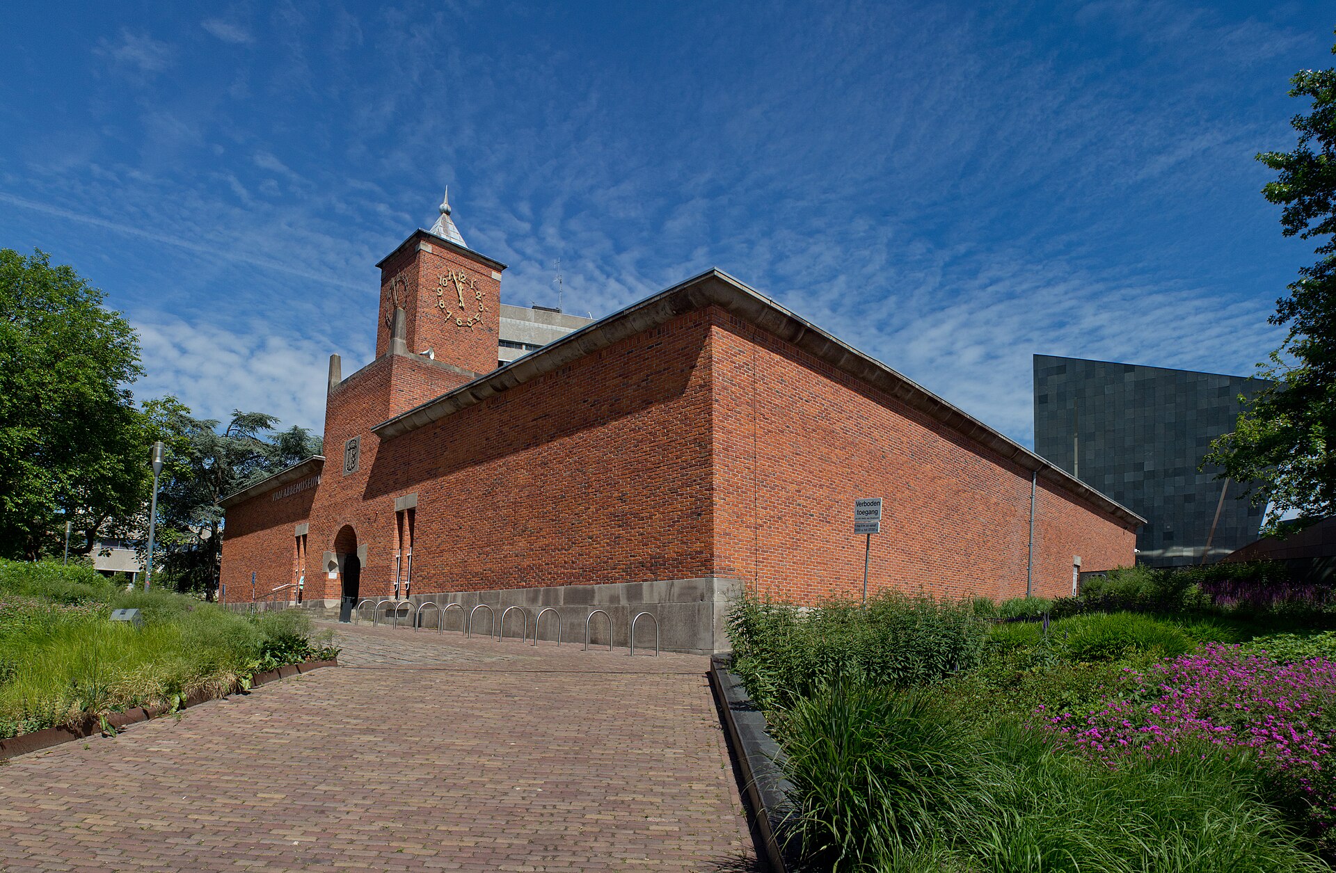The brick 1930s Van Abbemuseum building in Eindhoven with its clock tower and the dark modern extension behind