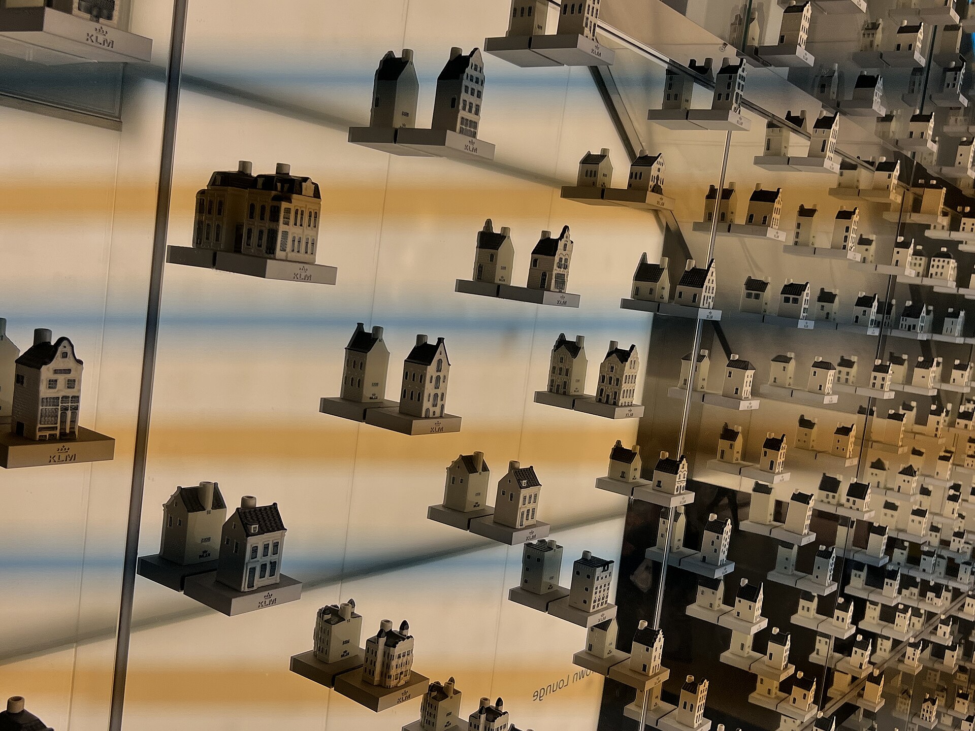 A glass wall of KLM Delft blue miniature canal houses at the Crown Lounge entrance
