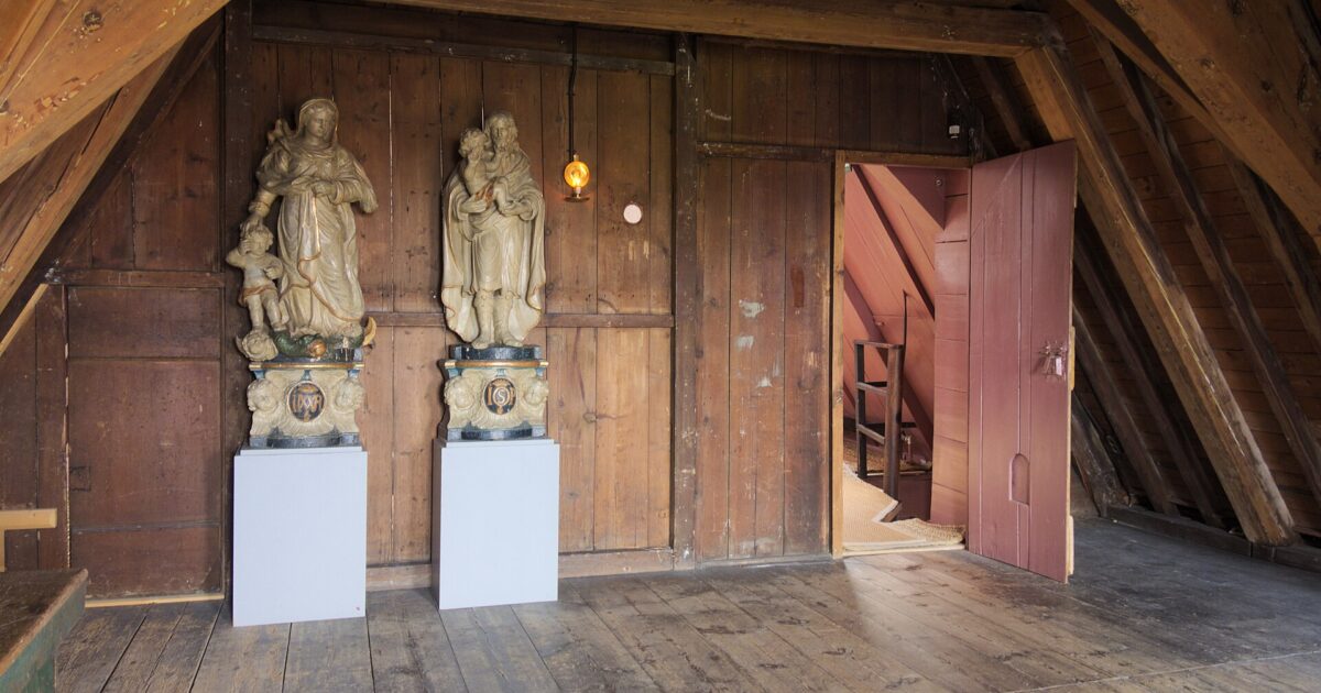 A bare wooden garret with roof timbers and two carved saints inside Our Lord in the Attic in Amsterdam
