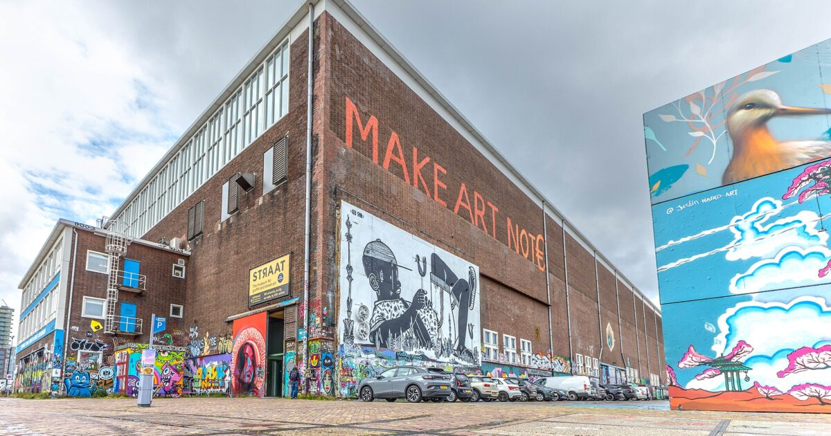The STRAAT Museum warehouse at NDSM in Amsterdam with a large mural reading Make Art Not Money